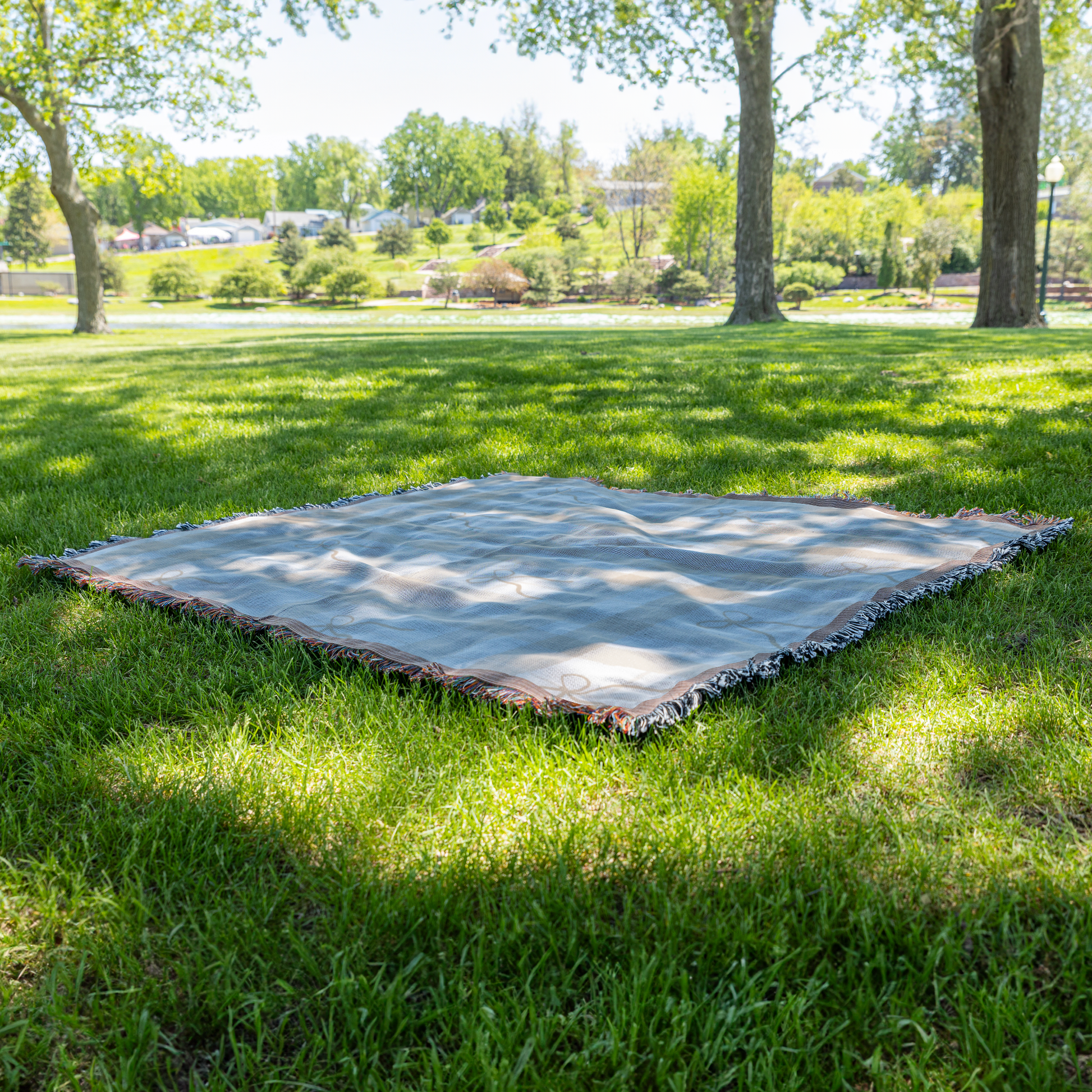 Dainty bows neutral woven throw blanket, on grass view